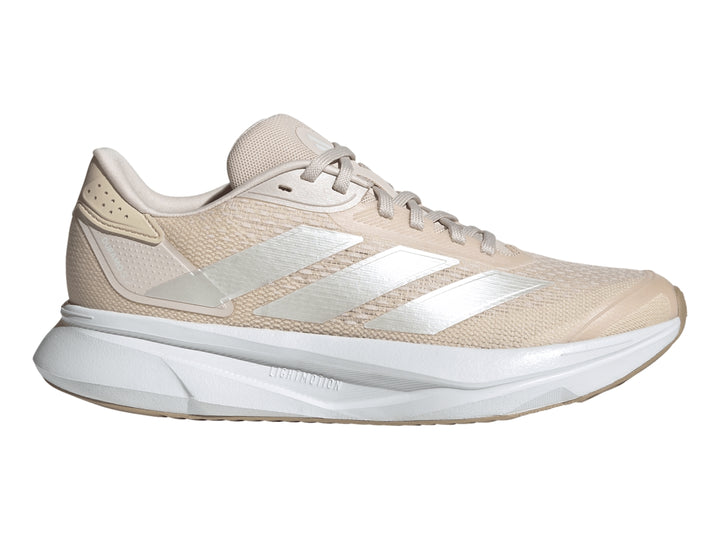 Tenis deportivos Adidas color beige con suela blanca y franjas plateadas laterales.
