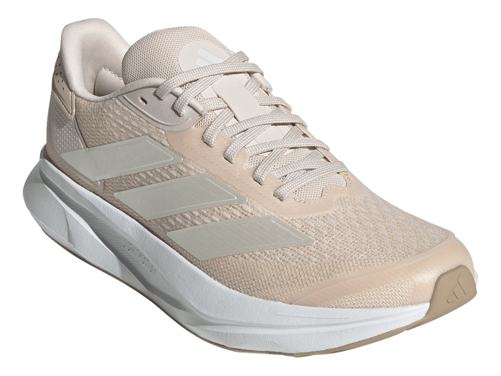 Tenis deportivos Adidas color beige con suela blanca y franjas plateadas laterales.
