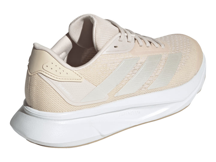 Tenis deportivos Adidas color beige con suela blanca y franjas plateadas laterales.