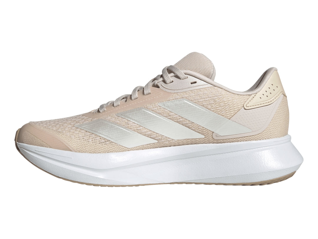 Tenis deportivos Adidas color beige con suela blanca y franjas plateadas laterales.