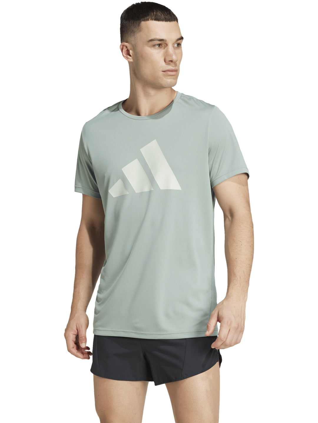 Hombre vistiendo playera deportiva Adidas color verde claro con logo blanco y shorts negros.