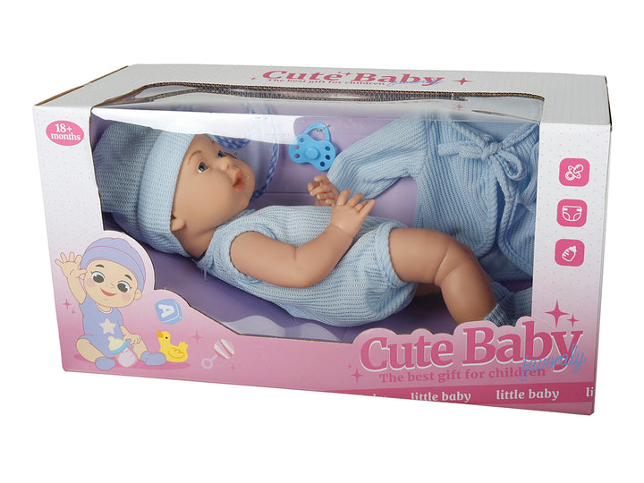 Muñeca bebé de color piel con ropa y gorro azul, incluye accesorios, presentada en caja transparente.