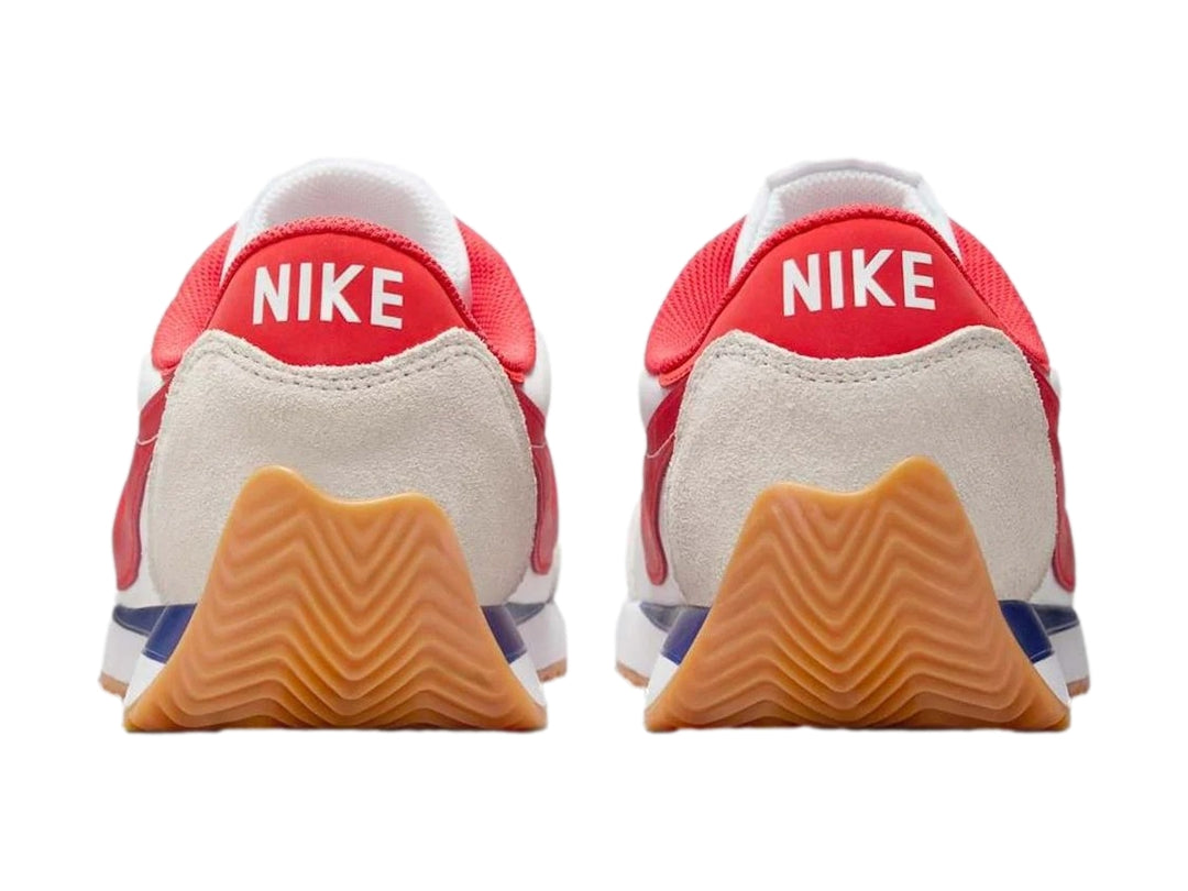 Tenis Nike blancos con detalles en gris, suela color miel y logotipo rojo en el costado.