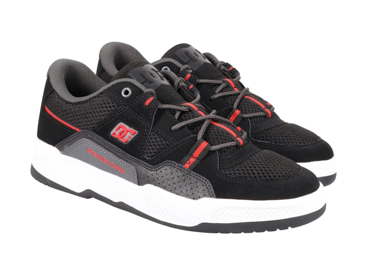 Tenis deportivos DC Shoes en color negro con detalles rojos y suela blanca.