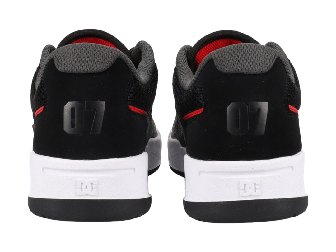 Tenis deportivos DC Shoes en color negro con detalles rojos y suela blanca.