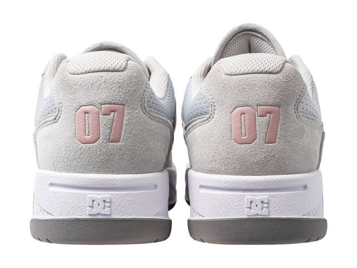 Tenis DC Shoes en color gris con detalles en rosa y suela blanca, vista lateral.