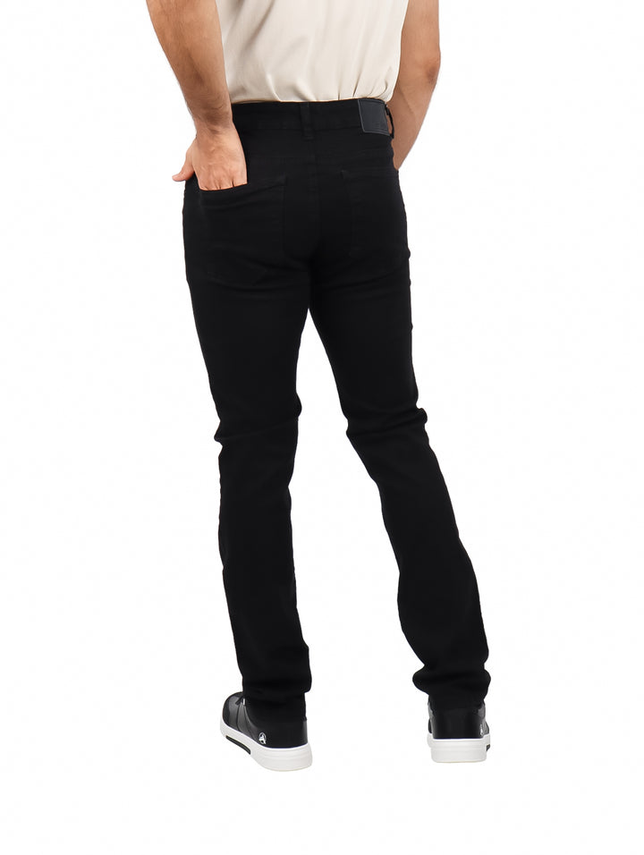 Hombre vistiendo pantalones jeans ajustados de color negro y calzado deportivo negro.