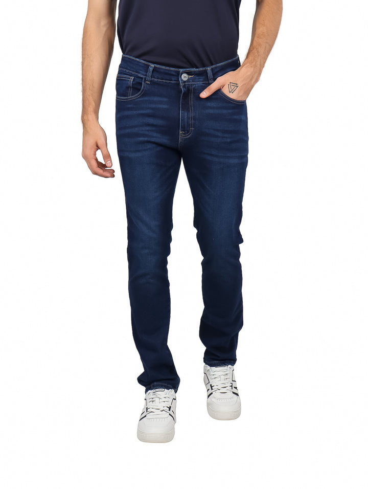 Hombre vistiendo pantalones de mezclilla color azul índigo y tenis blancos.