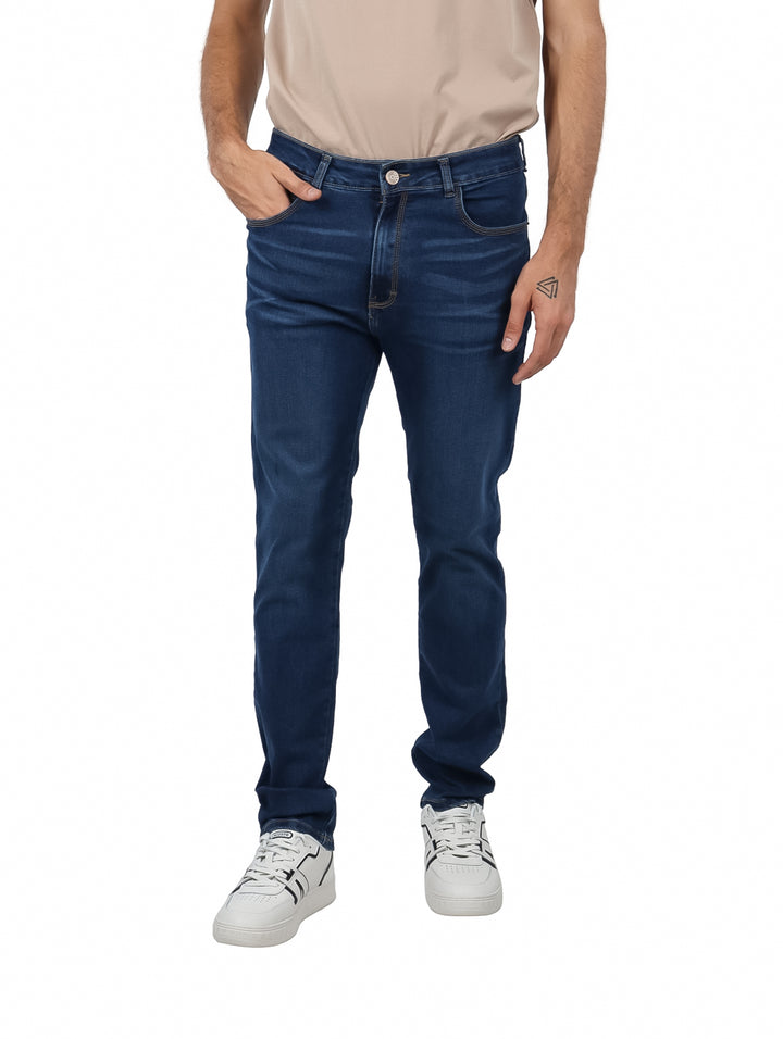 Hombre vistiendo pantalones jeans azul oscuro y tenis blancos sobre fondo blanco.