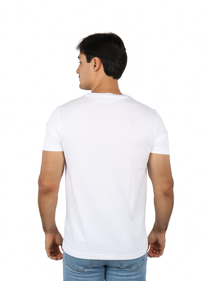 Hombre vistiendo una camiseta blanca de manga corta con un logotipo colorido de cocodrilo en el pecho.