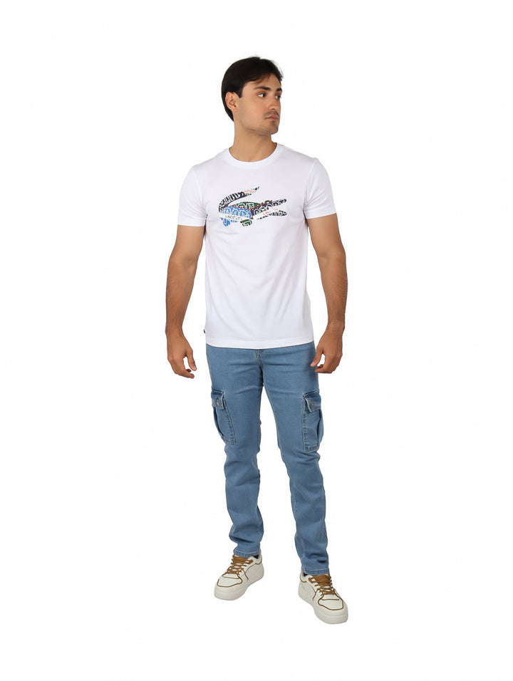 Hombre vistiendo una camiseta blanca de manga corta con un logotipo colorido de cocodrilo en el pecho.