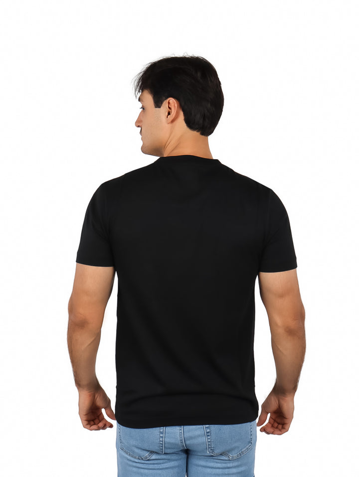 Hombre vistiendo una camiseta negra de manga corta con un logotipo grande de cocodrilo naranja en el pecho.