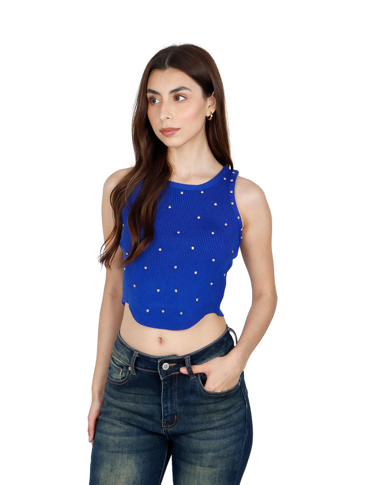 Mujer vistiendo un crop top azul royal acanalado con detalles brillantes y jeans azules.