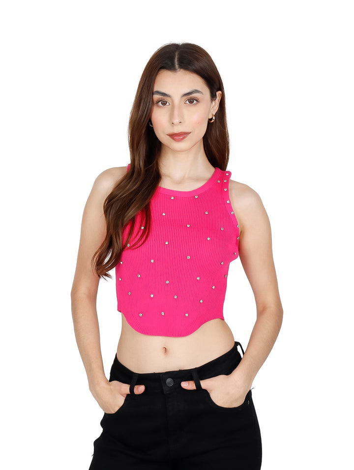 Mujer vistiendo un crop top fucsia acanalado con pequeños detalles brillantes y pantalones negros.