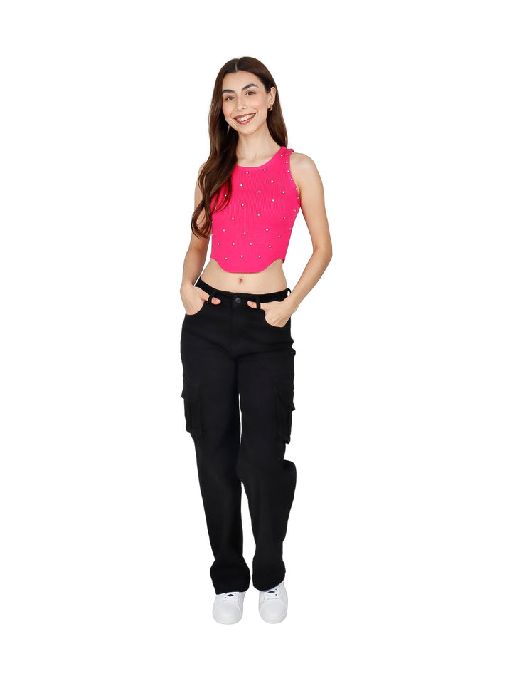 Mujer vistiendo un crop top fucsia acanalado con pequeños detalles brillantes y pantalones negros.