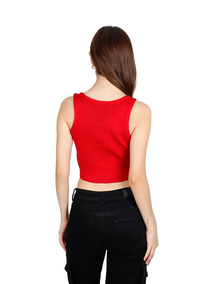 Mujer vistiendo un crop top rojo sin mangas con pequeños detalles brillantes y pantalones negros.