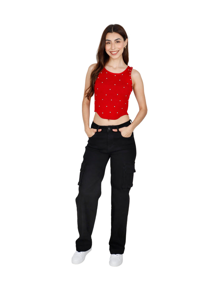 Mujer vistiendo un crop top rojo sin mangas con pequeños detalles brillantes y pantalones negros.