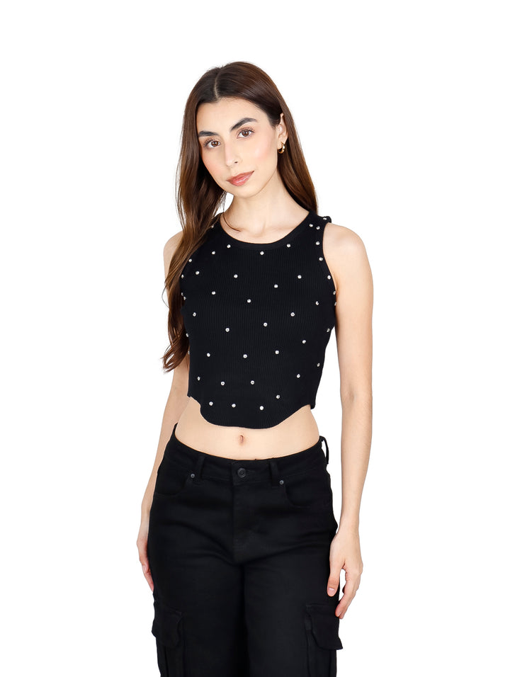Mujer vistiendo un crop top negro sin mangas con pequeños detalles brillantes y pantalones negros.