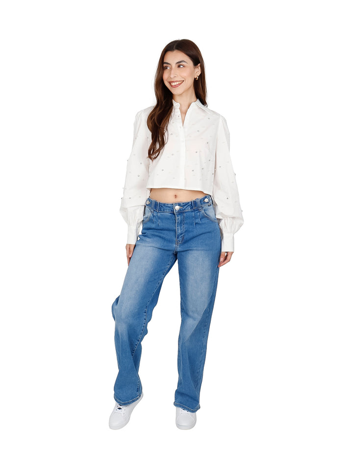 Mujer vistiendo una camisa crop top blanca con detalles de perlas y mangas largas.