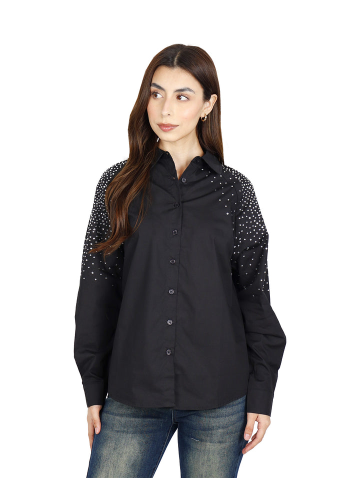Mujer vistiendo camisa oversize color negro con detalles de puntos blancos en las mangas.