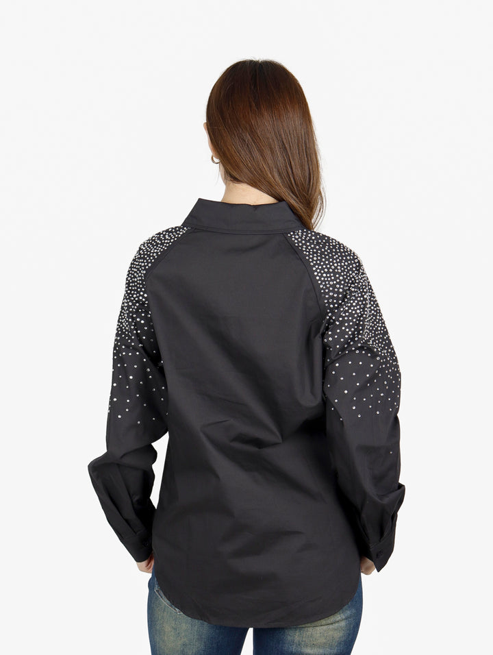 Mujer vistiendo camisa oversize color negro con detalles de puntos blancos en las mangas.