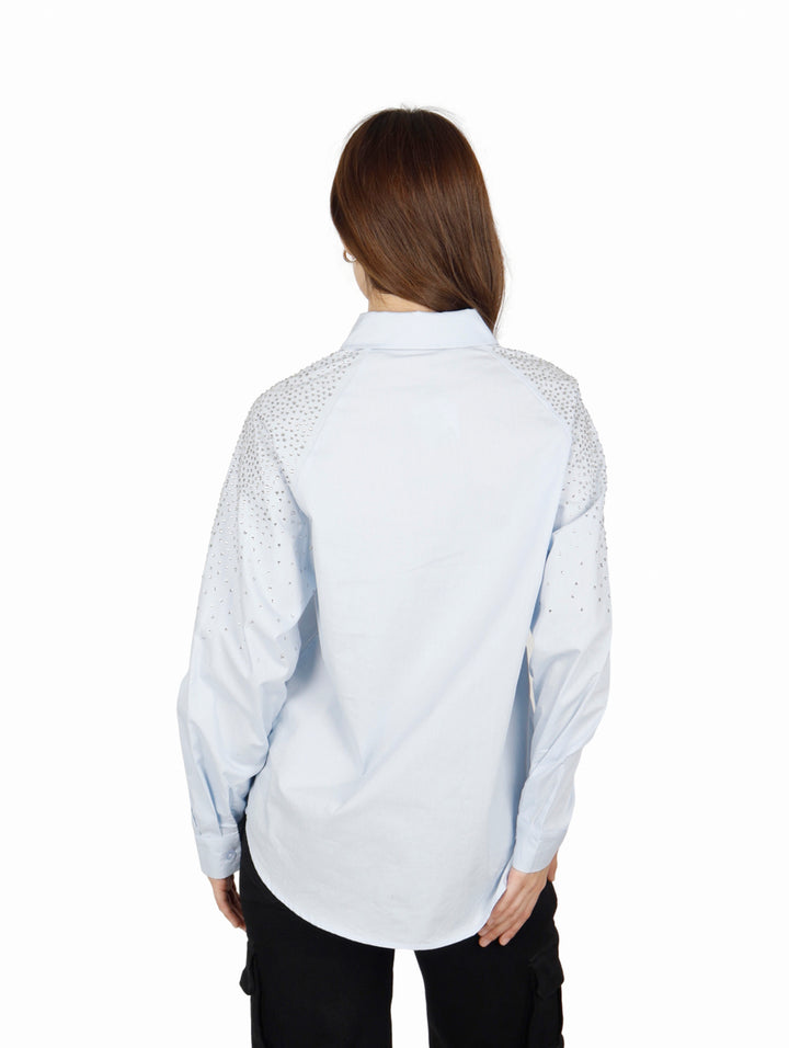 Camisa oversize color azul claro para mujer con detalles brillantes en el hombro.