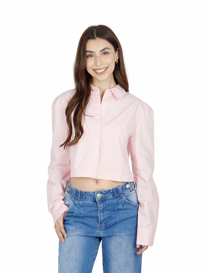 Mujer vistiendo una camisa cropped de color rosa claro con cuello y manga larga.