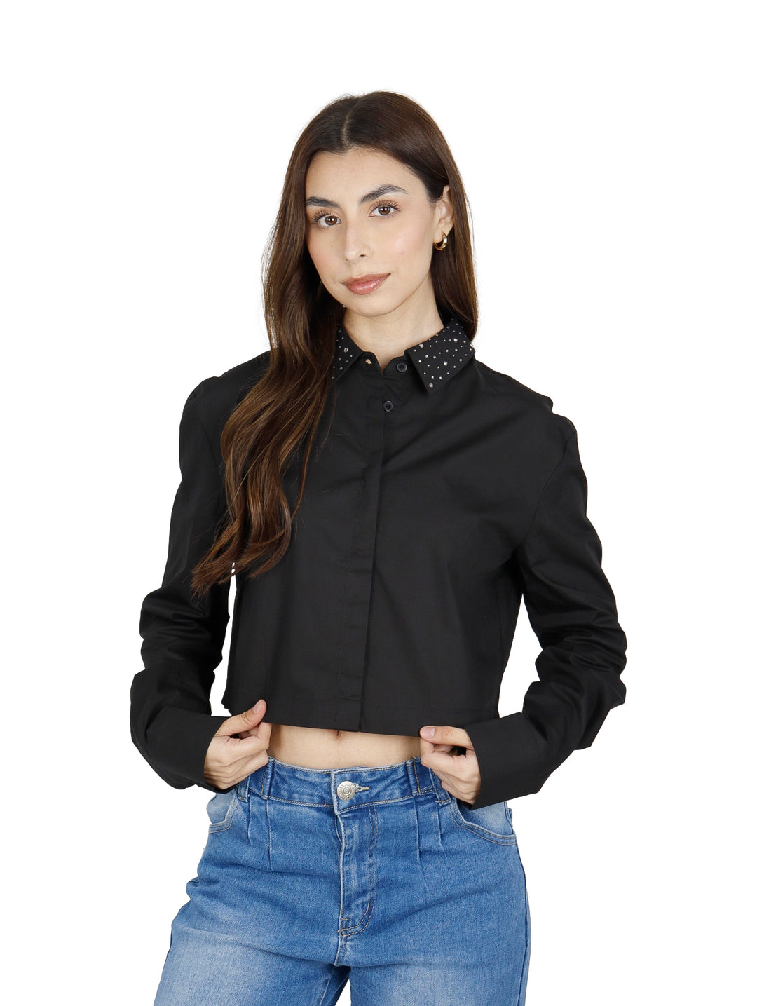 Mujer vistiendo una camisa corta negra de manga larga con cuello de lunares blancos y jeans azules.