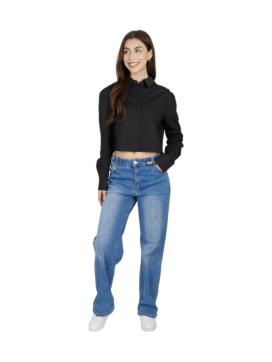 Mujer vistiendo una camisa corta negra de manga larga con cuello de lunares blancos y jeans azules.