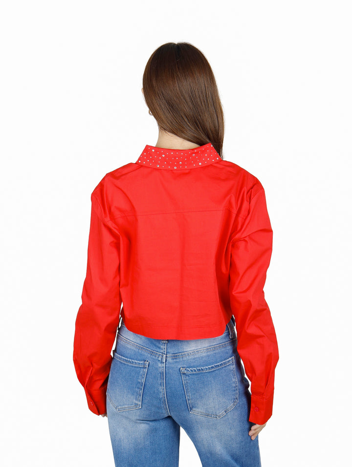Mujer vistiendo una camisa roja corta de manga larga con botones.
