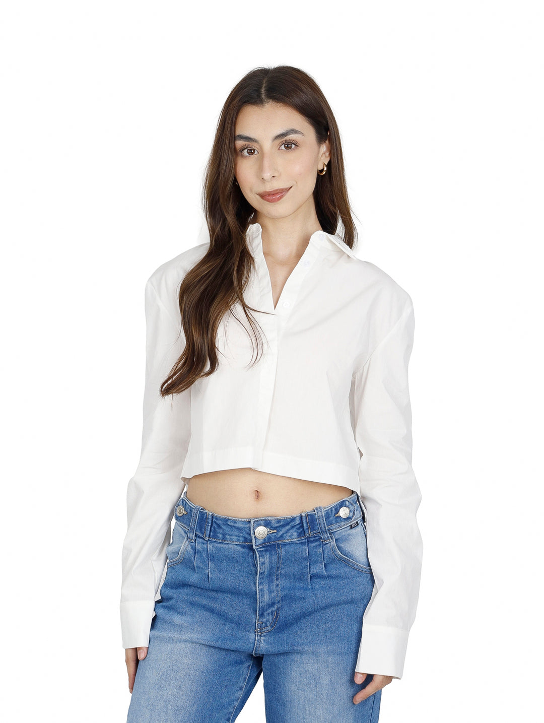 Mujer vistiendo una camisa blanca corta de manga larga y pantalones vaqueros azules.