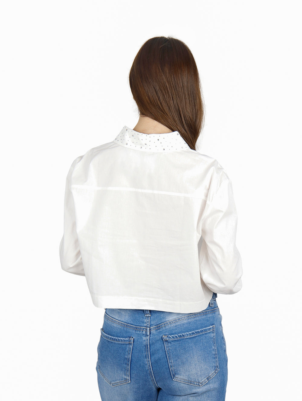 Mujer vistiendo una camisa blanca corta de manga larga y pantalones vaqueros azules.