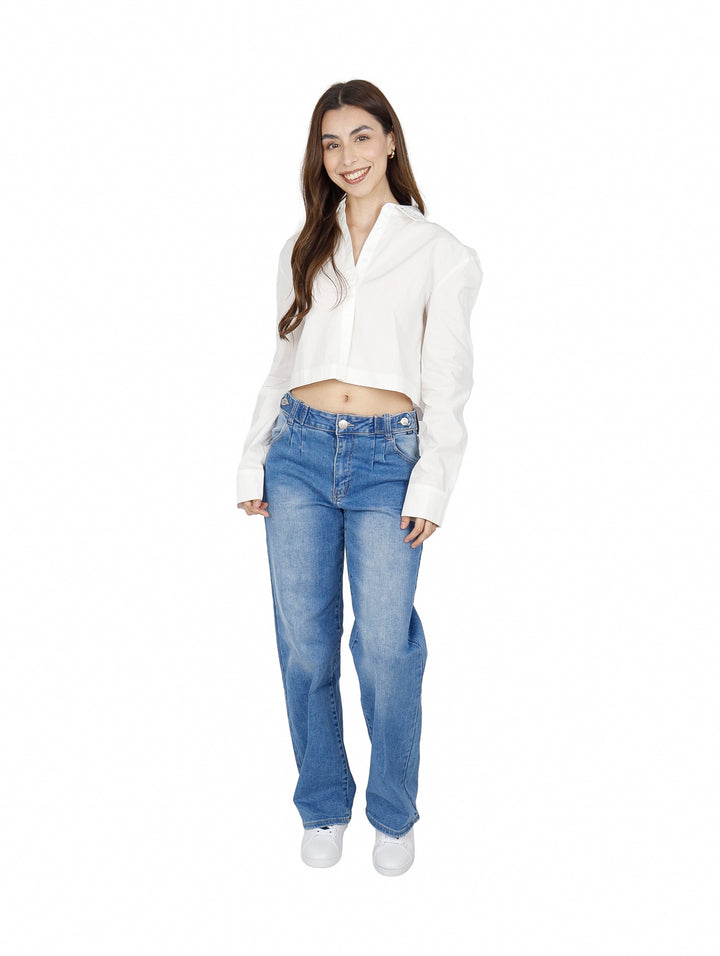 Mujer vistiendo una camisa blanca corta de manga larga y pantalones vaqueros azules.