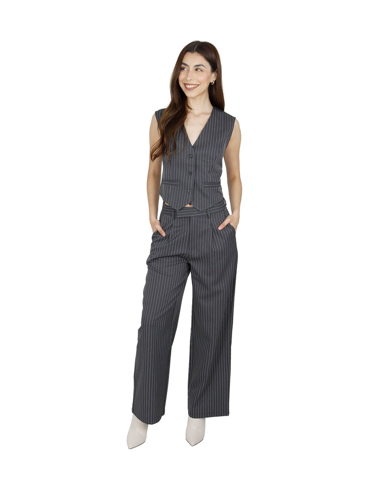 Mujer vistiendo un chaleco gris oxford con rayas diplomáticas y pantalones a juego.