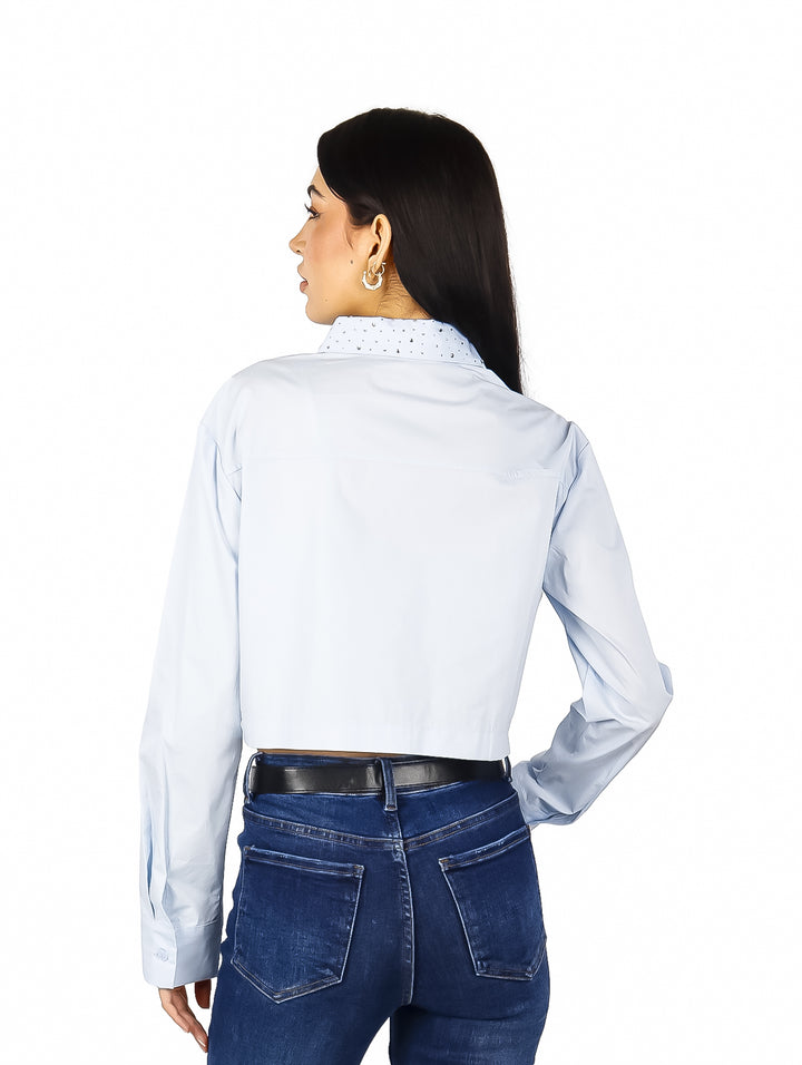 Mujer vistiendo una camisa cropped de color azul claro con manga larga y cuello.
