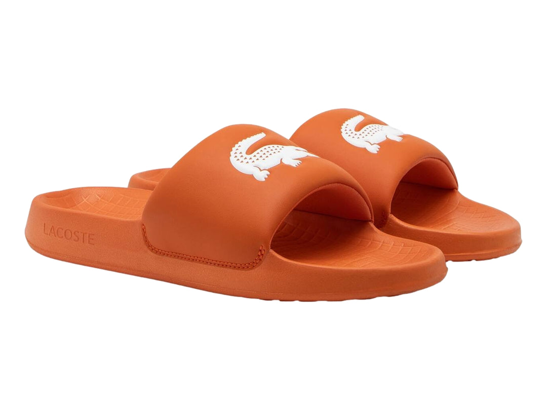 Sandalia deslizante Lacoste de color naranja con logotipo blanco en la banda superior.