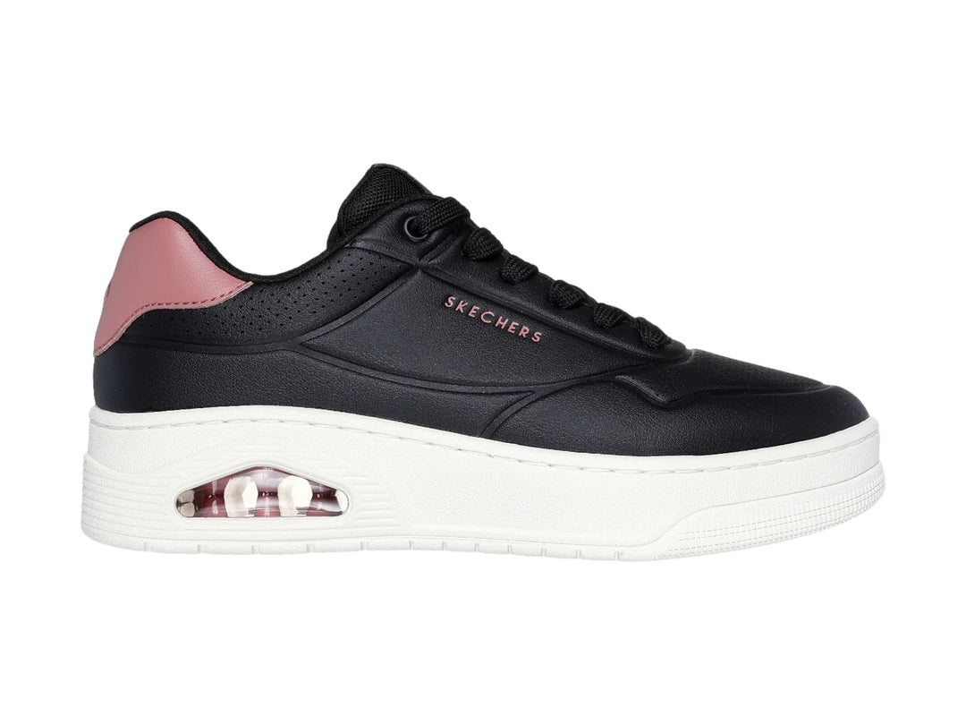Tenis Skechers color negro con suela blanca y detalle en rosa en el talón.