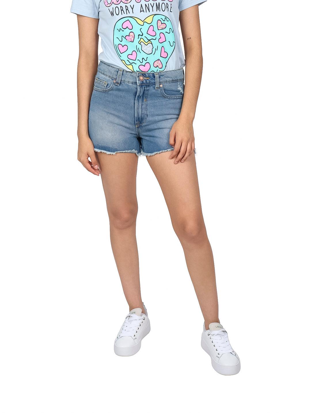 Mujer vistiendo shorts de mezclilla azul claro con acabado doble stone y bordes deshilachados.