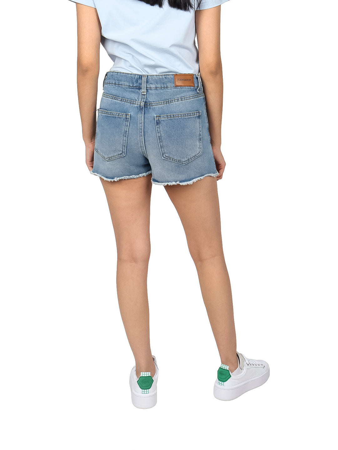 Mujer vistiendo shorts de mezclilla azul claro con acabado doble stone y bordes deshilachados.