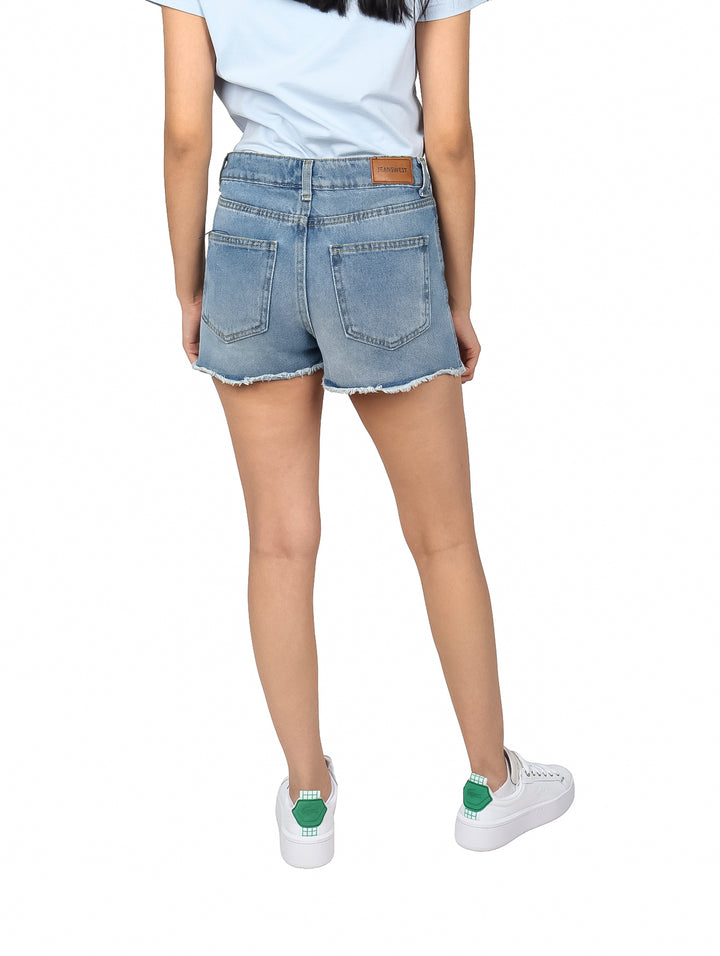 Mujer vistiendo shorts de mezclilla azul claro con acabado doble stone y bordes deshilachados.