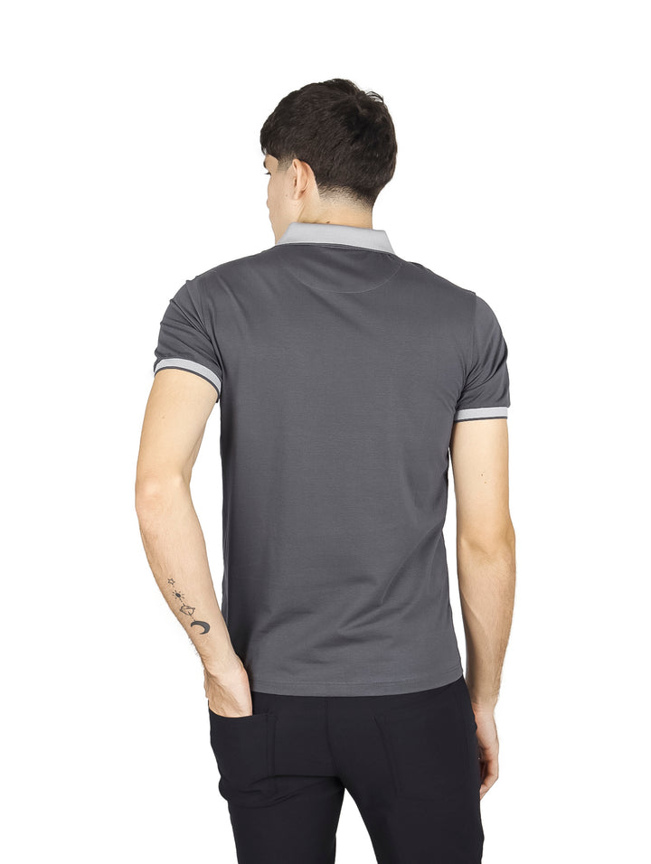 Hombre vistiendo playera polo color charcoal con detalles en gris claro en el cuello y los bordes de las mangas.