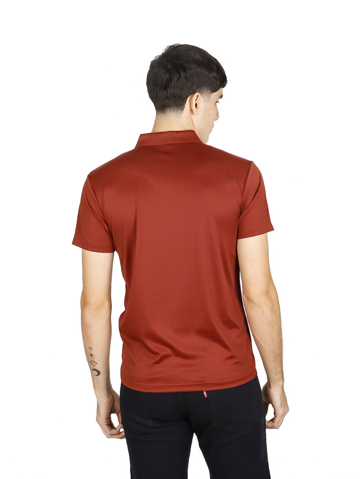 Hombre vistiendo una playera polo de color terracota y pantalones negros sobre fondo blanco.