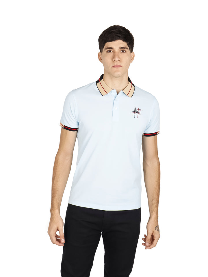 Hombre vistiendo playera polo color azul cielo con detalles negros y rojos en el cuello y mangas.