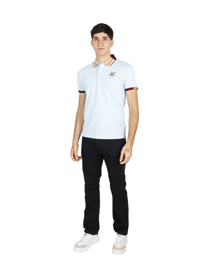 Hombre vistiendo playera polo color azul cielo con detalles negros y rojos en el cuello y mangas.