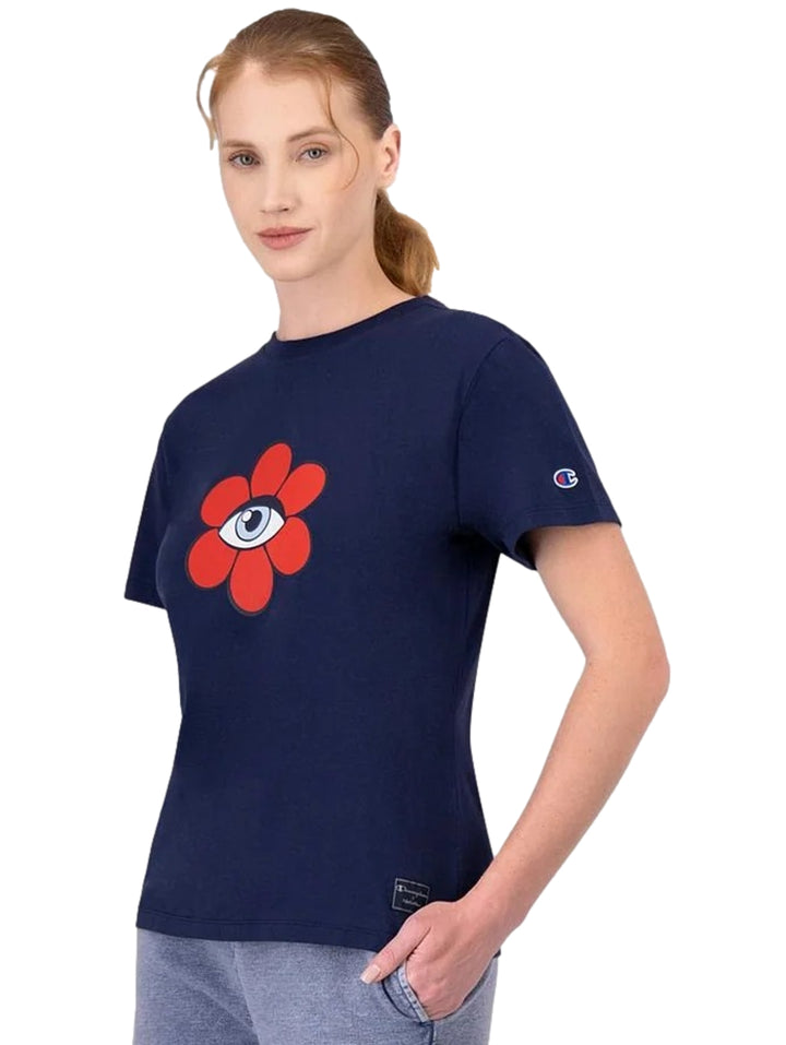 Mujer vistiendo playera Champion azul marino con un diseño de flor roja en el pecho.