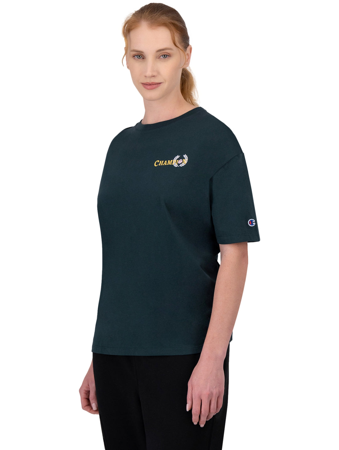 Mujer vistiendo una camiseta deportiva de color verde oscuro con logotipo de Champion en el pecho y manga.