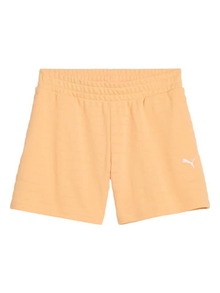 Mujer vistiendo shorts deportivos PUMA color albaricoque de talle alto, con calcetines blancos y tenis negros.