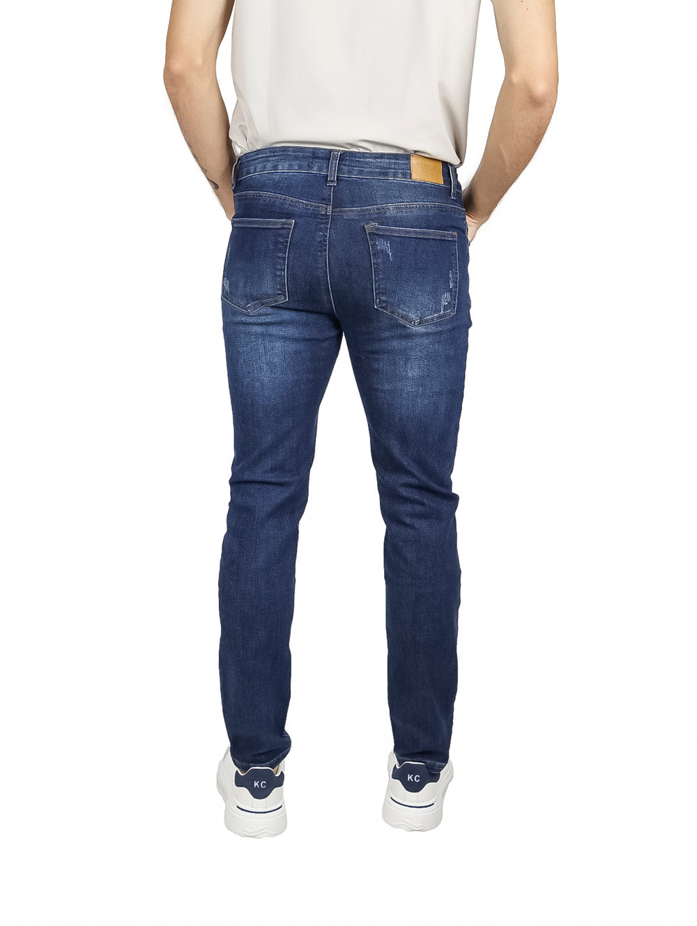Hombre vistiendo pantalones jeans slim fit color índigo con efecto deslavado.