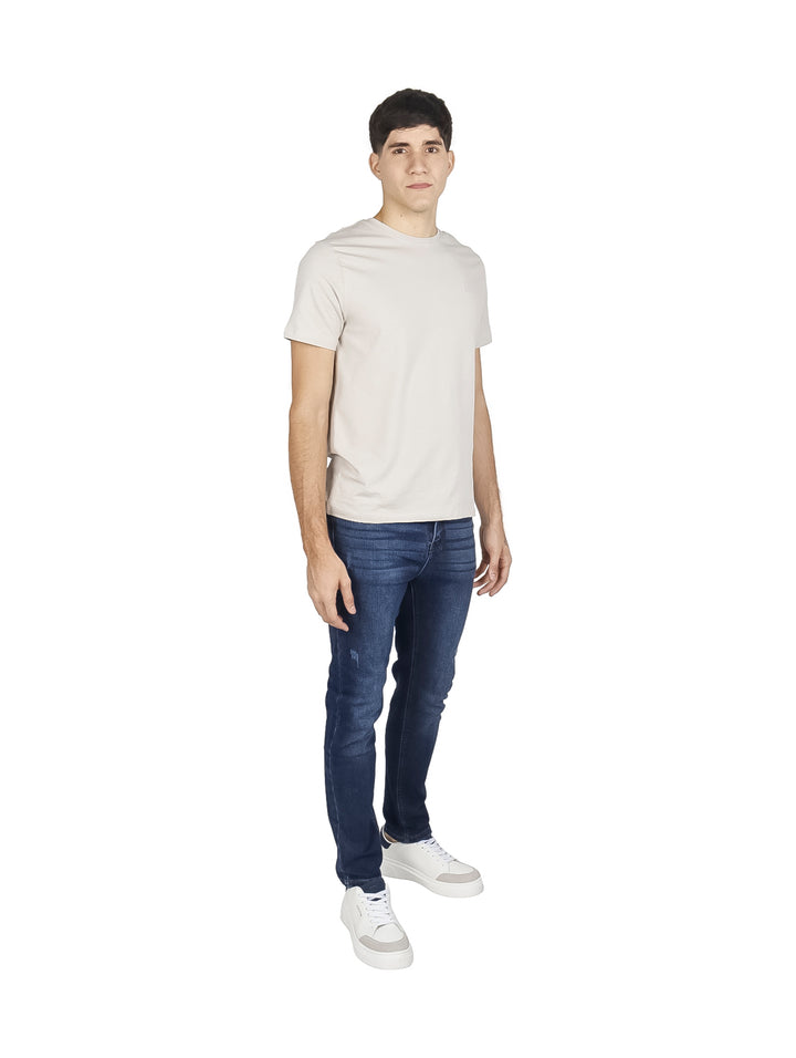Hombre vistiendo pantalones jeans slim fit color índigo con efecto deslavado.