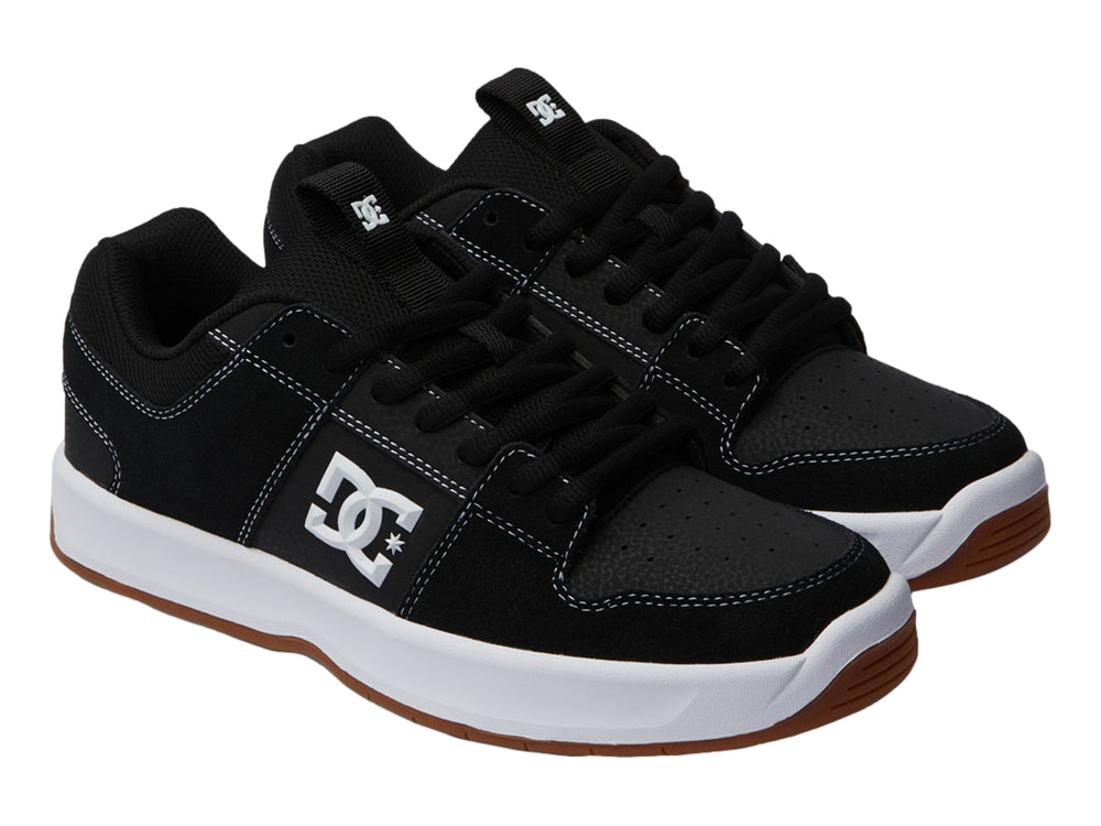 Tenis DC Shoes color negro con suela blanca y base café, vista lateral.